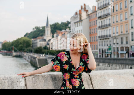 Femme debout sur la passerelle sur la rivière contre les bâtiments en ville Banque D'Images