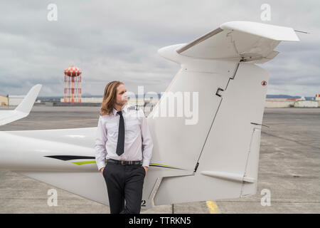 Certain male pilot in airplane par permanent sur la piste de l'aéroport contre ciel nuageux Banque D'Images