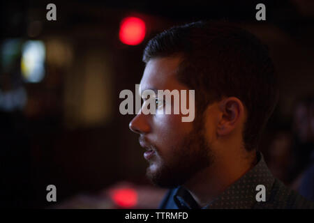 Close-up of man looking away while standing outdoors at night Banque D'Images