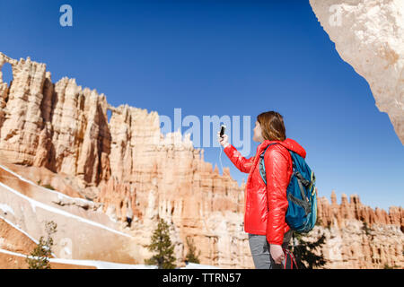 Low angle view of hiker photographing par téléphone mobile à Bryce Canyon National Park Banque D'Images