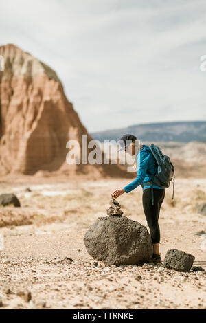 Vue latérale du female hiker stacking les rochers tandis que l'article dans le desert Banque D'Images