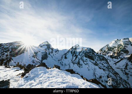 Flare soleil au sommet d'une montagne enneigée dans les rocheuses Banque D'Images