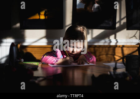 Fille écrit sur papier à table Banque D'Images