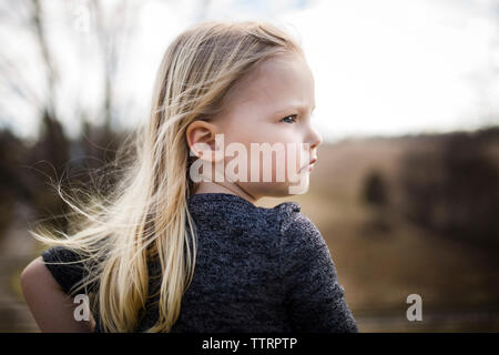 Vue arrière du girl looking away while standing on field Banque D'Images