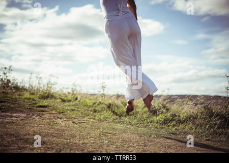 La section basse de femme sautant sur terrain Banque D'Images