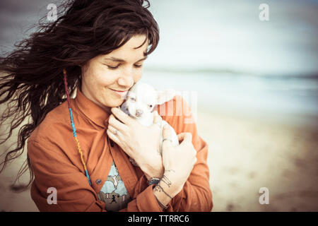 Woman holding puppy tout en se tenant à la ciel nuageux Banque D'Images