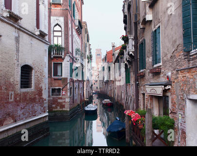 Bateaux amarrés à canal étroit au milieu des immeubles d'habitation en ville Banque D'Images