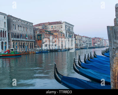 Gondoles amarré au grand canal par des bâtiments contre ciel clair Banque D'Images