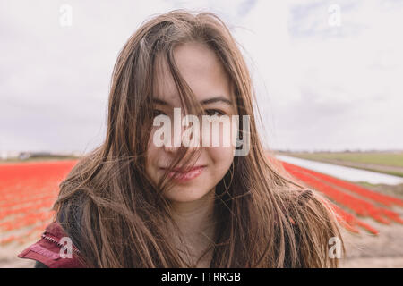 Jeune femme debout sur le champ pays avec le vent dans les cheveux. Banque D'Images