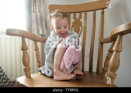 Girl wrapped in towel assis sur une chaise à la maison Banque D'Images