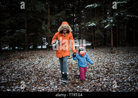 Mère et fille dans des vêtements chauds durant l'hiver de la forêt à pied Banque D'Images