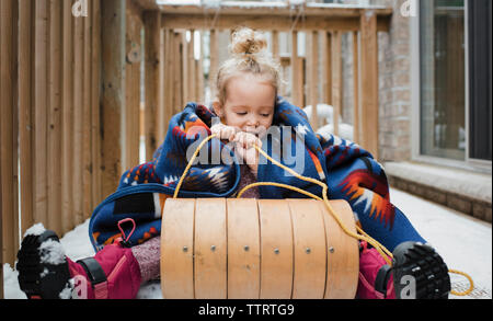 Fille assise sur un traîneau au patio Banque D'Images