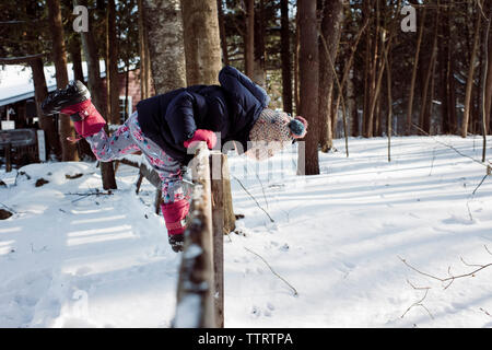 Vue latérale de flexion de fille en se tenant sur le grillage en hiver Banque D'Images