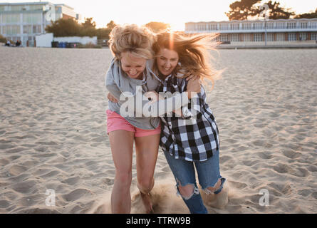 Happy female friends running on sand at beach Banque D'Images