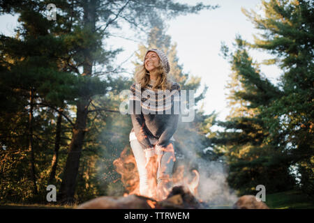 Happy woman standing by camp contre des arbres en forêt Banque D'Images