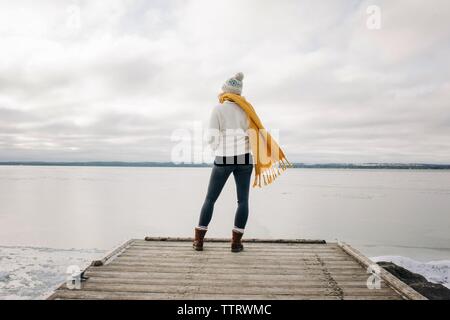 Femme debout à l'extrémité d'une jetée à la jetée dehors à l'eau Banque D'Images