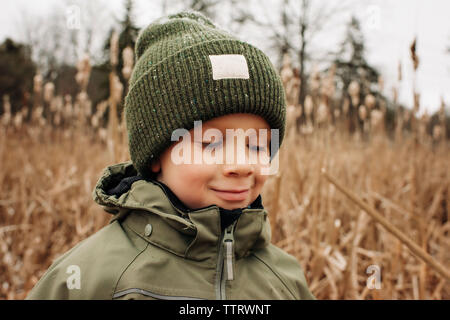 Portrait of young boy smiling en hiver avec chapeau et manteau dans la neige Banque D'Images