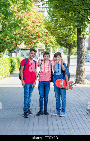 Portrait of smiling friends standing sur trottoir en ville Banque D'Images