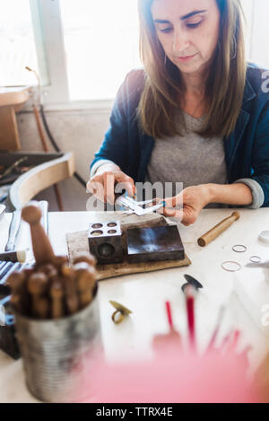 Portrait de femme de bijoutier bague avec étrier du workbench en atelier Banque D'Images