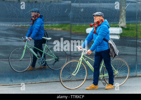 Senior man wearing blue Jacket balade vélo sur un trottoir de la ville Banque D'Images