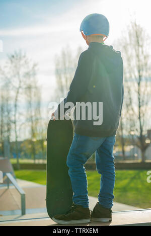 Vue arrière d'un jeune patineur avec casque tout en se tenant à la rampe de skate Banque D'Images