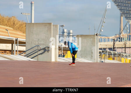 Vue latérale du sportif fatigué man with hand on knee Banque D'Images