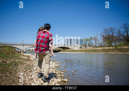 Toute la longueur du père fille comptable en marchant sur le pont et rivière contre ciel bleu clair au cours de journée ensoleillée Banque D'Images