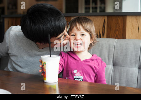 Les baisers heureux père fille, alors qu'assis à table dans cafe Banque D'Images