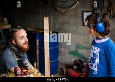 High angle view of blacksmith parler à boy in workshop Banque D'Images