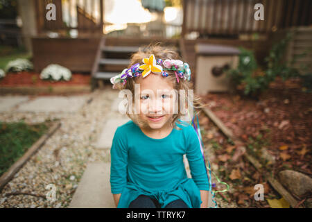 Une adorable petite fille yeux avec une bande de fleurs autour de la tête Banque D'Images