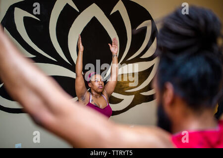 Une femme dans une classe de yoga étire ses bras jusqu'à un yoga pose Banque D'Images