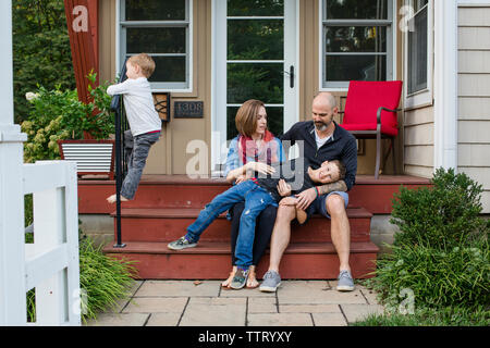 Une famille heureuse s'asseoir ensemble sur avant stoop Banque D'Images