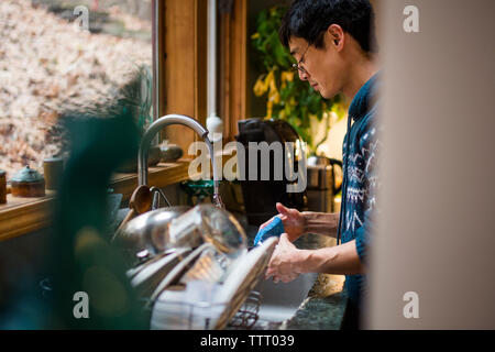 Vue latérale d'un homme lave-vaisselle dans la cuisine devant une fenêtre Banque D'Images