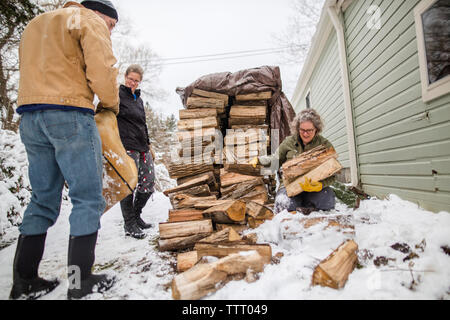 Une famille travaillent ensemble pour ramasser le bois d'une cheminée en hiver Banque D'Images