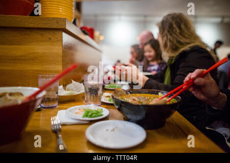 Famille de manger le dîner ensemble au restaurant asiatique à long compteur Banque D'Images