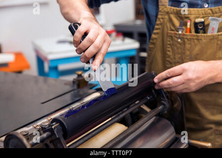 L'homme l'application de peinture sur des machines dans la presse à imprimer Banque D'Images