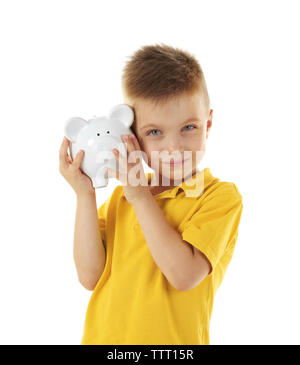 Concept d'épargne. Cute boy en jaune T-shirt holding piggy bank isolated on white Banque D'Images