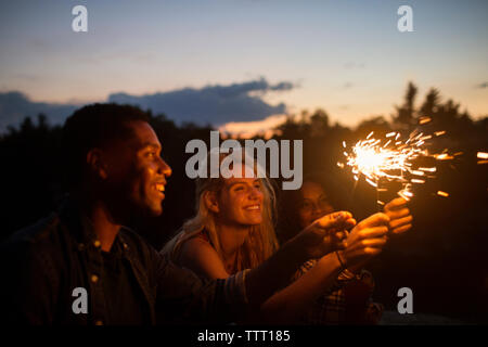 Happy friends holding allumé cierges au crépuscule Banque D'Images