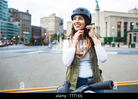 Woman wearing helmet debout avec vélo en ville Banque D'Images