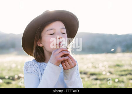 Close-up of Girl with eyes closed blowing dandelion seed debout contre le ciel au cours de journée ensoleillée Banque D'Images
