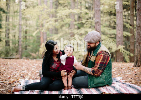 Heureux parents à la fille à manger tout en vous relaxant sur contrat cadre dans la forêt Banque D'Images