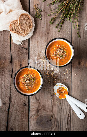 Vue de dessus de carottes dans des bols avec du pain et de romarin sur table en bois Banque D'Images