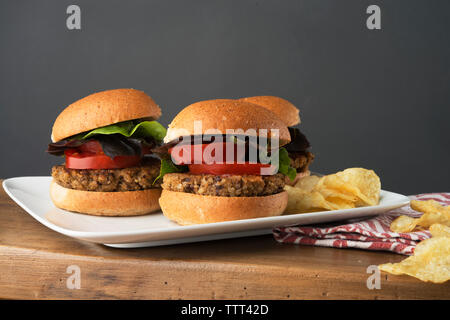 Close-up of veggie burgers avec croustilles de pommes de terre servis sur table en bois Banque D'Images