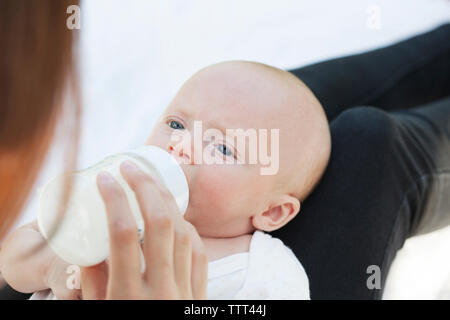 Portrait de Mère nourrir bébé assis à park Banque D'Images