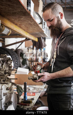 Homme sérieux partie machine huilage à l'atelier de réparation Banque D'Images