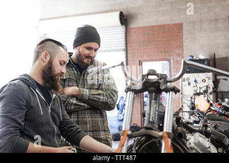 L'homme à la recherche de mécanicien à travailler sur la moto à l'atelier de réparation automobile Banque D'Images