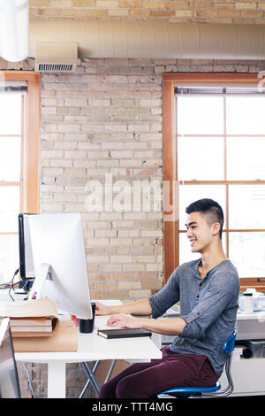 homme d'affaires utilisant l'ordinateur de bureau tout en travaillant dans le bureau Banque D'Images