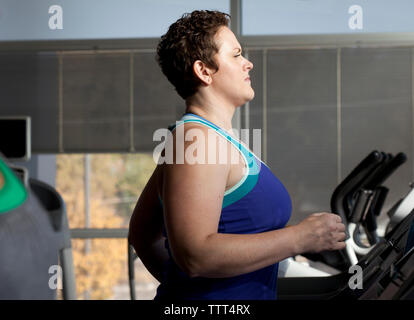 Vue latérale de l'exercice sur tapis roulant femme curvy Banque D'Images
