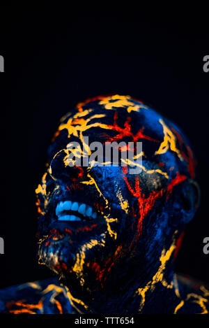 Portrait conceptuel d'un homme peint de couleurs UV fluorescent et ressemble à de la lave au néon Banque D'Images