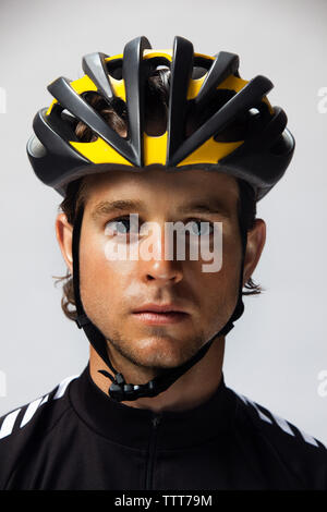 Portrait of smiling cyclist wearing helmet against white background Banque D'Images